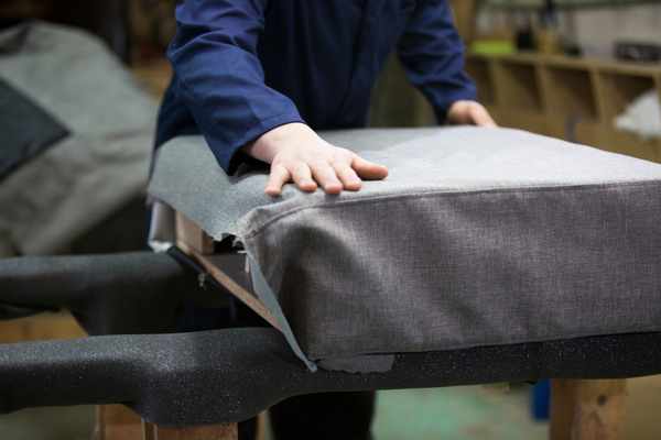 A person applying upholstery on a sofa cushion